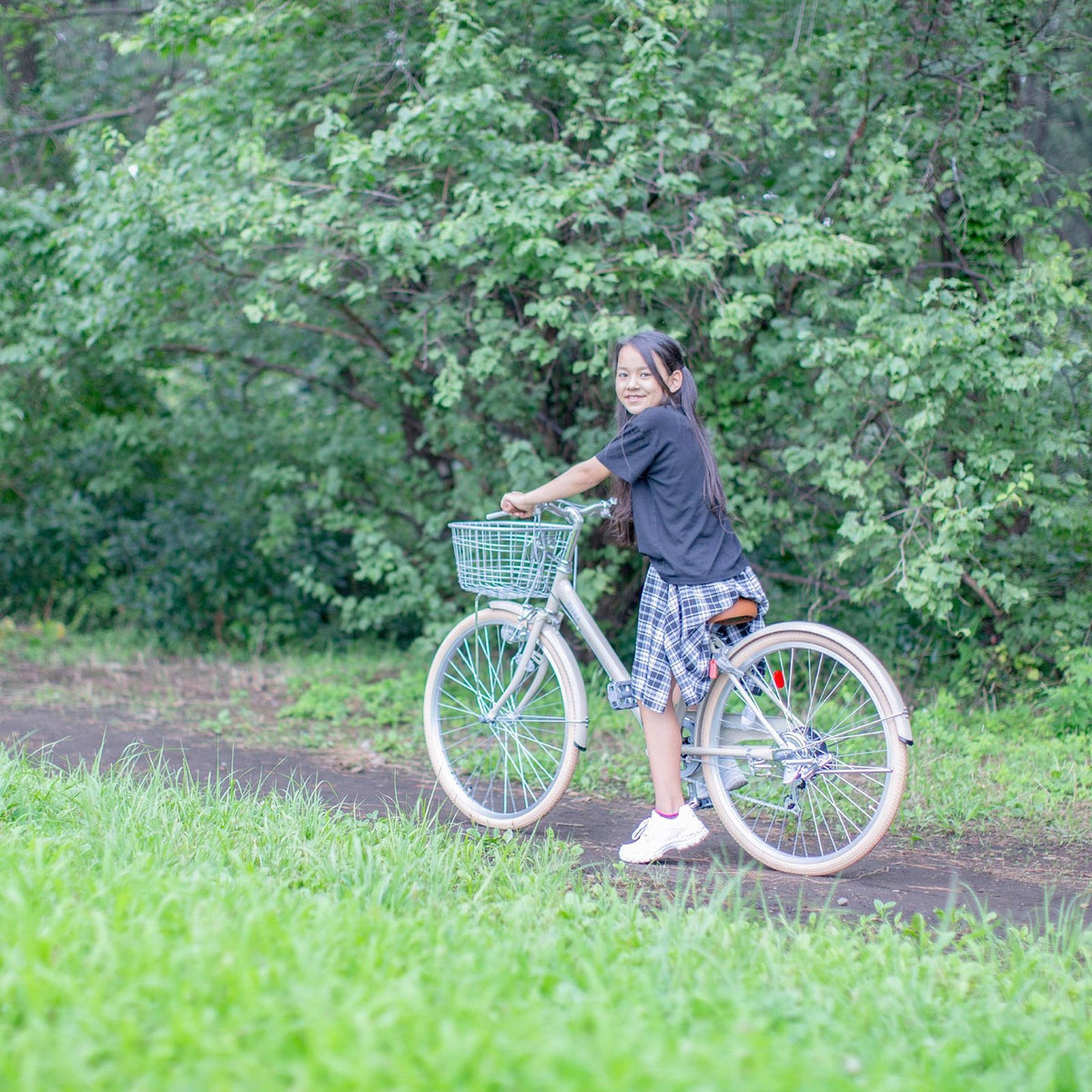 草地で自転車を押す女の子